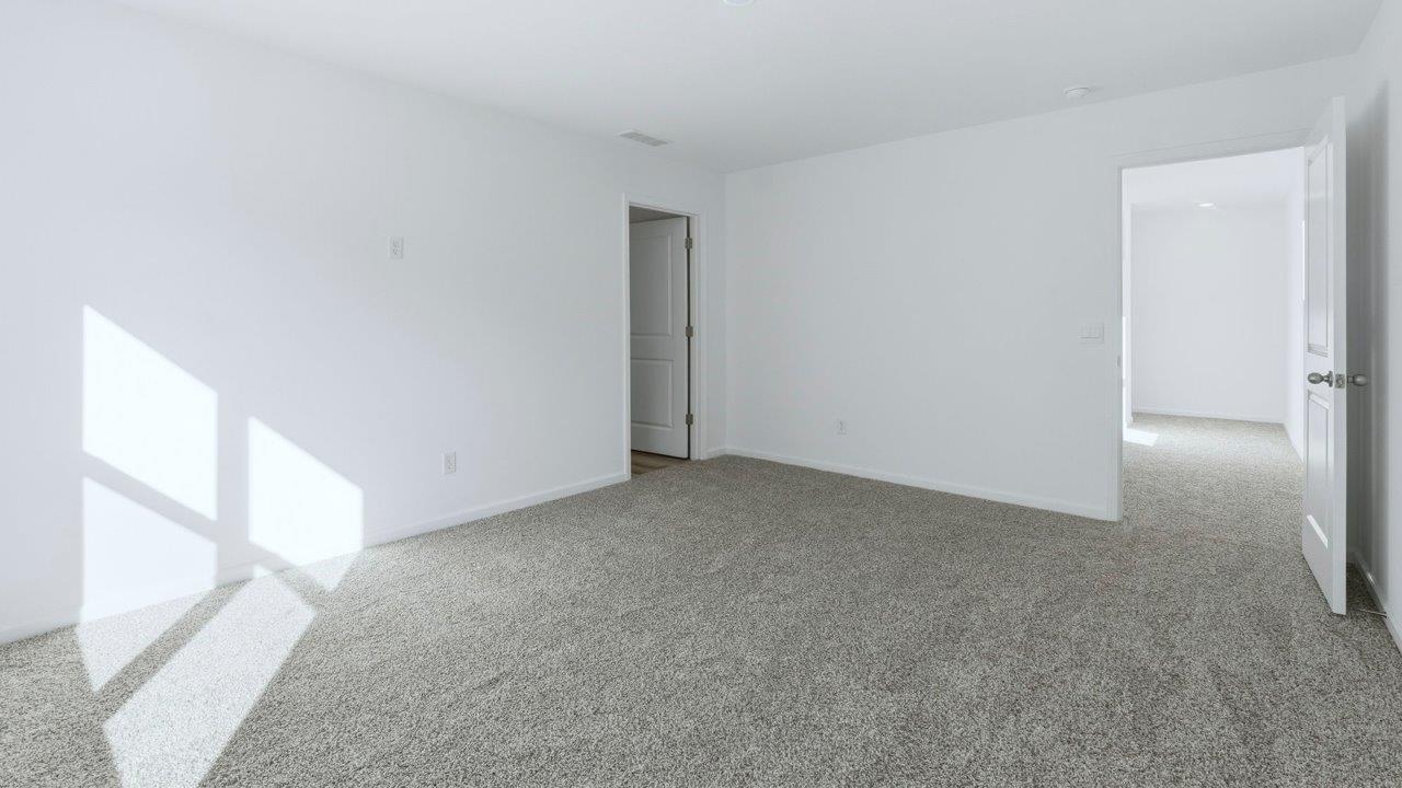 primary bedroom with carpet and ensuite bath and walk in closet