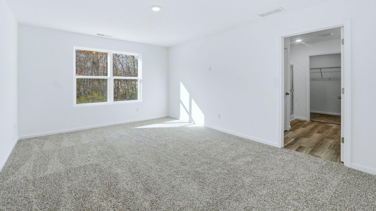 primary bedroom with carpet and ensuite bath and walk in closet