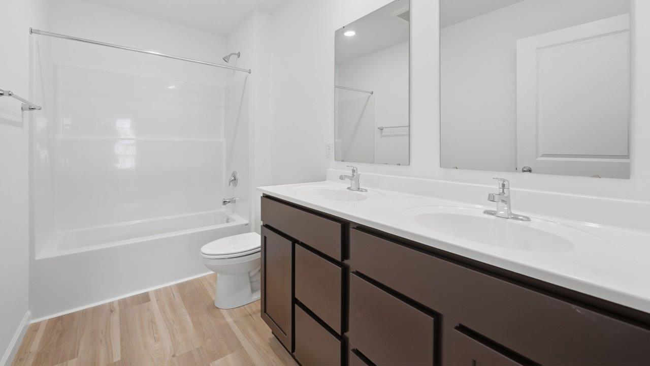 kennebec elm second floor full bathroom with dual vnaity sink, tub shower, sarsaparilla cabinets, white marble counters, and mohawk avery lvp flooring