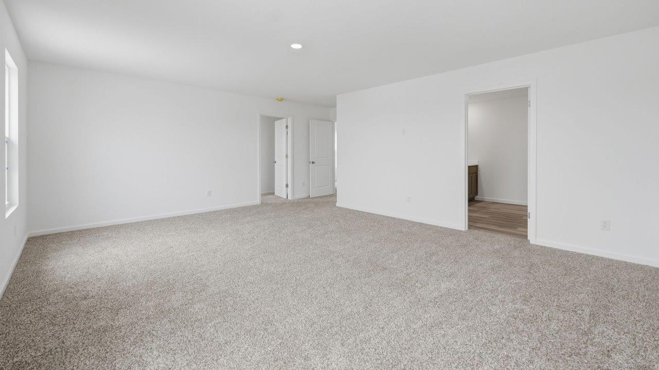 kennebec elm primary bedroom with carpet flooring, white walls, and ensuite bathroom and walk in closet