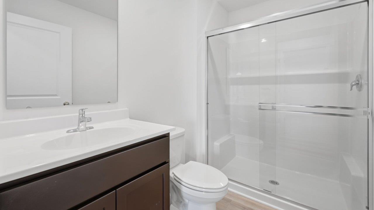 kennebec elm first floor full bathroom with single vanity sink, sarsaparilla cabinets, white marble countertops, and walk in fiberglass shower
