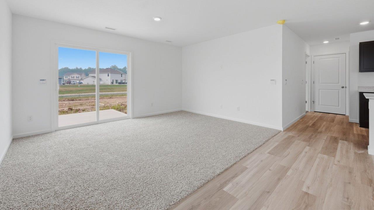 kennebec elm open layout living room with carpet flooring, white walls, and sliding glass door to backyard patio