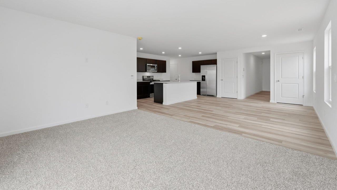 kennebec elm open layout living room with foreman everstrand elk beige carpet and dining room and kitchen with mohawk avery lvp flooring