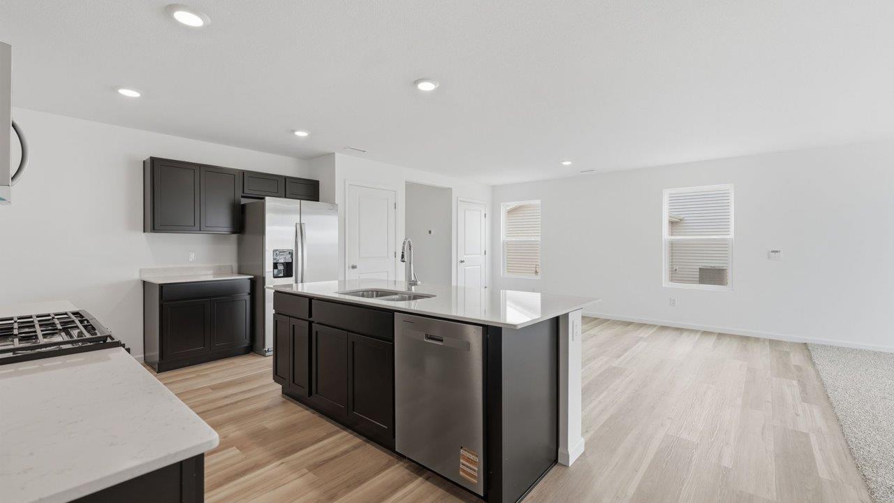 kennebec elm kitchen with sarsaparilla cabinets, stainless steel appliances, quartz countertops, and island with bar seating