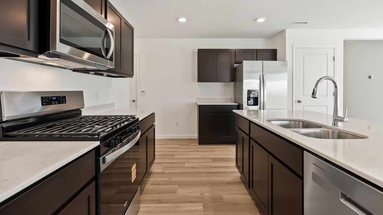 Kennebec Elm C3 - kitchen with sarsaparilla cabinets, quartz countertops, island with bar seating, and stainless steel appliances