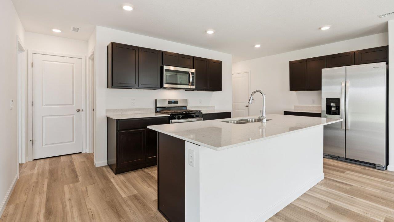 Kennebec Elm C3 - kitchen with sarsaparilla cabinets, quartz countertops, island with bar seating, and stainless steel appliances