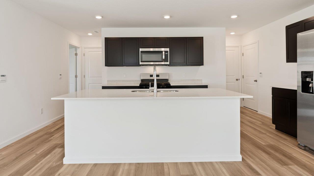 Kennebec Elm C3 - kitchen with sarsaparilla cabinets, quartz countertops, island with bar seating, and stainless steel appliances