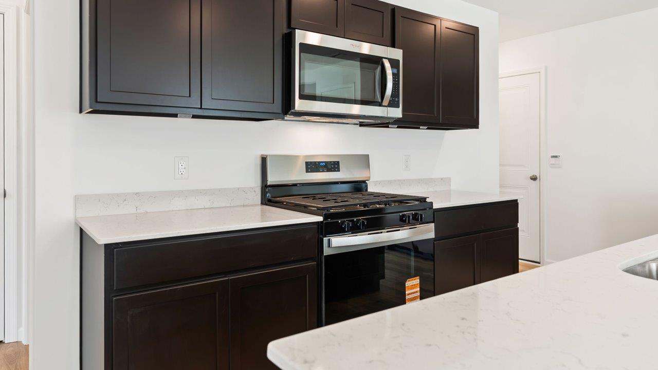 Kennebec Elm C3 - kitchen with sarsaparilla cabinets, quartz countertops, island with bar seating, and stainless steel appliances