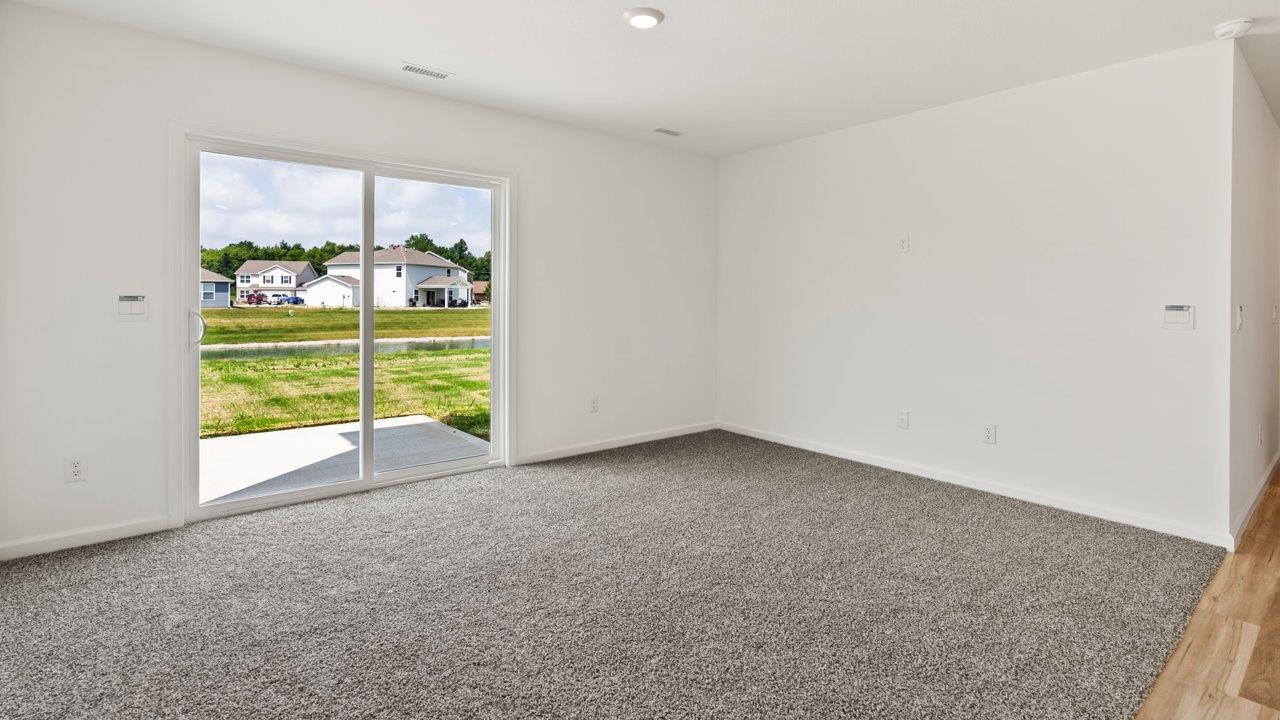 Kennebec Elm C3 - open layout living room with carpet flooring and sliding glass door to backyard patio