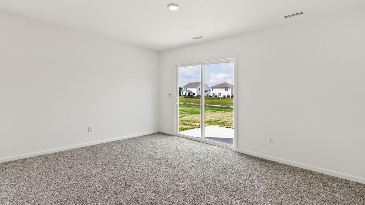 Kennebec Elm C3 - open layout living room with carpet flooring and sliding glass door to backyard patio