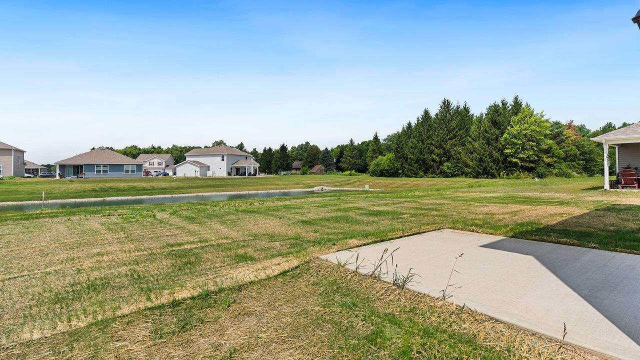 Kennebec Elm C3 - rear exterior concrete patio and seeded backyard with pond view