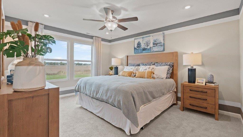 Chatham primary bed with carpet, fan, and large windows