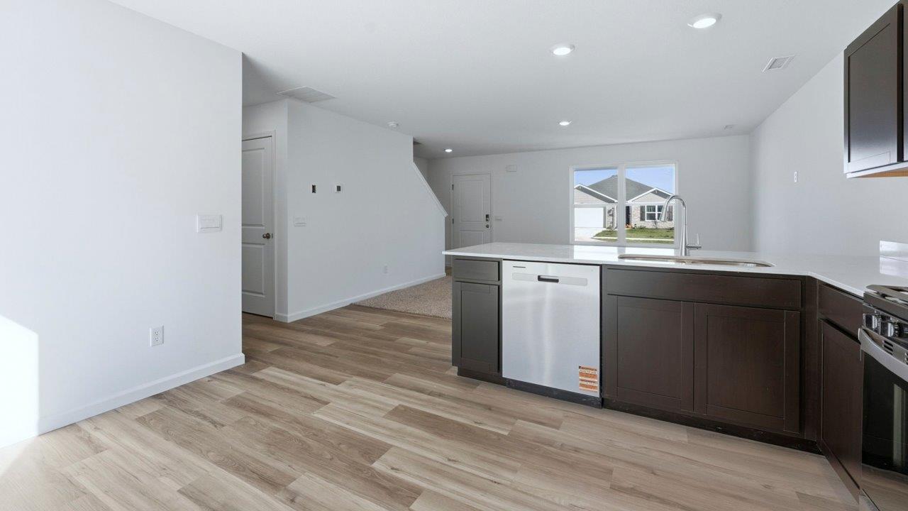 kitchen with sarsaparillla cabinets, quartz counters, lvp flooring, and stainless steel appliances