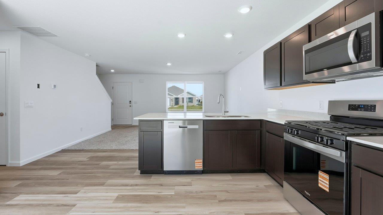 kitchen with sarsaparillla cabinets, quartz counters, lvp flooring, and stainless steel appliances