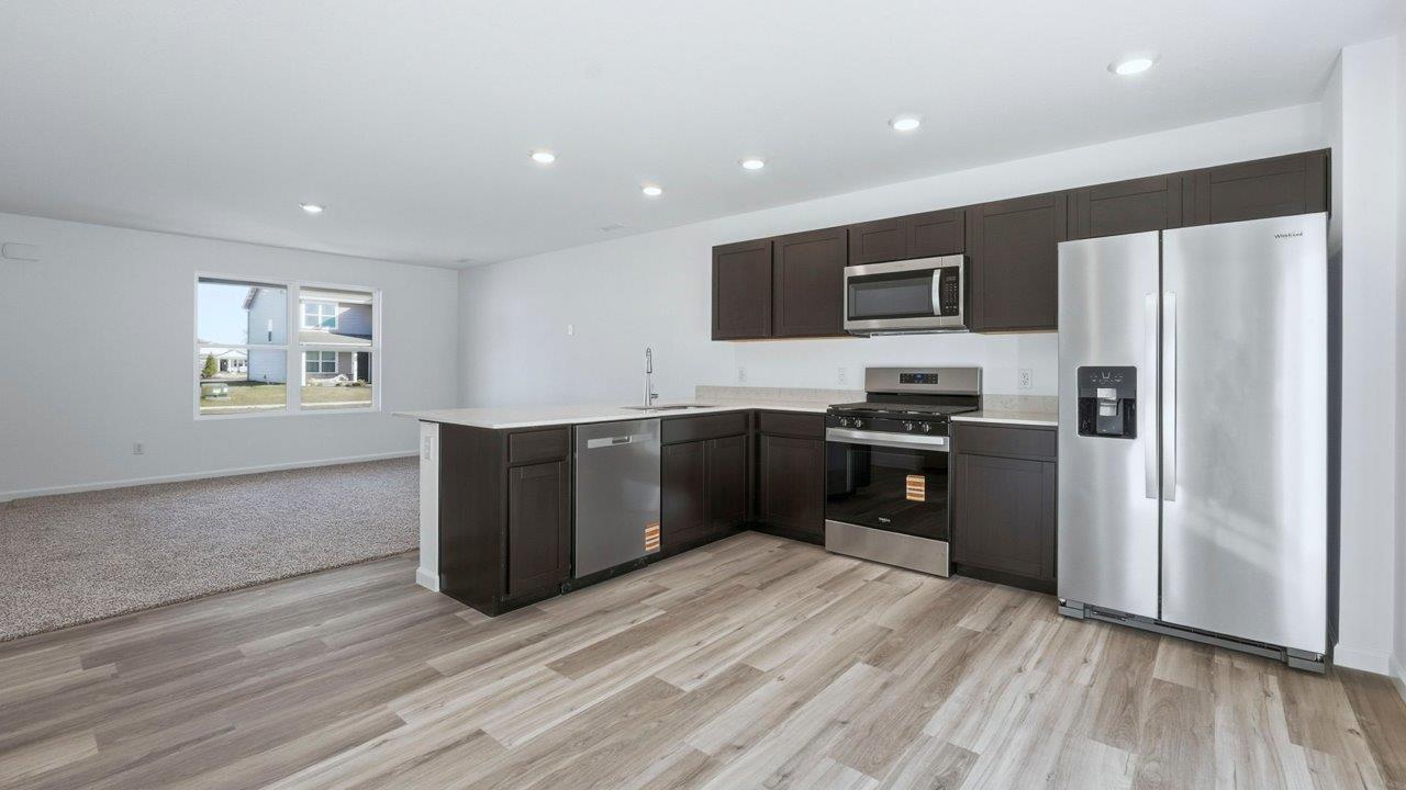 kitchen with sarsaparillla cabinets, quartz counters, lvp flooring, and stainless steel appliances