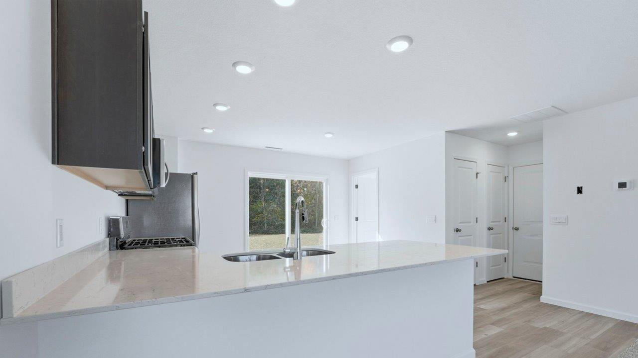 kitchen with sarsaparillla cabinets, quartz counters, lvp flooring, and stainless steel appliances
