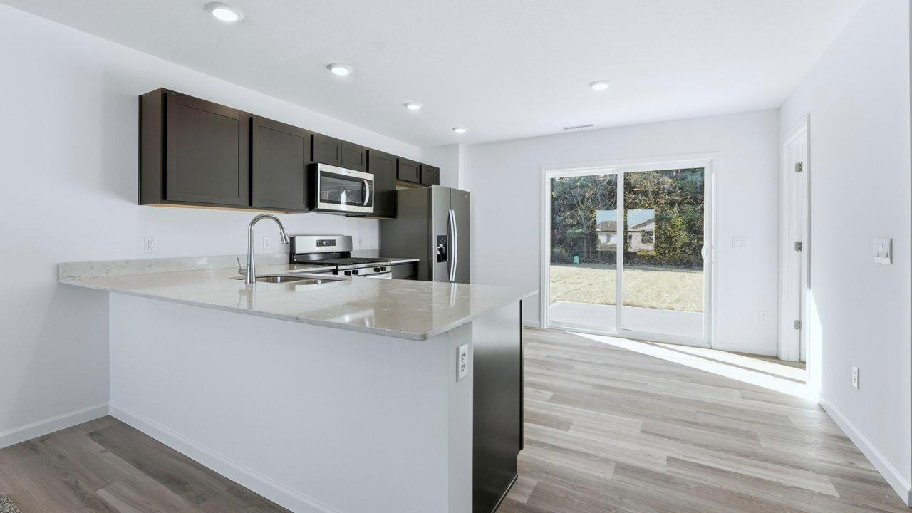 kitchen with sarsaparillla cabinets, quartz counters, lvp flooring, and stainless steel appliances