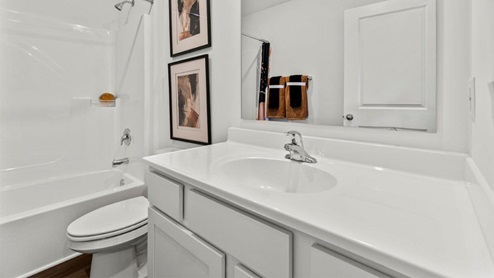 Riverwalk Villas Aldridge Model Home - Full bathroom with white cabinets, tub shower, and LVP flooring.