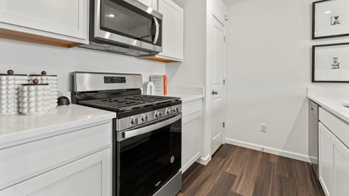 Riverwalk Villas Aldridge Model Home - Kitchen with white cabinets and stainless steel appliances.