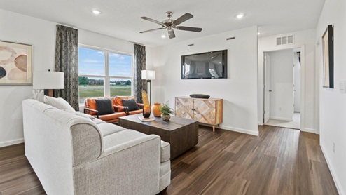 Riverwalk Villas Aldridge Model Home - Living room with 52in fan and 2 large windows bringing in natural light.