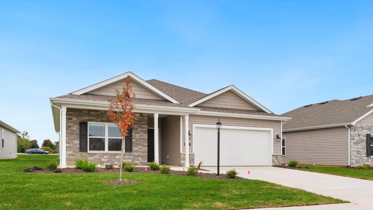 riverwalk villas harmony b3 exterior with covered patio, 2 car garage, sod yard, landscaping, heather vinyl siding, heather shake, and glacial bluff stone