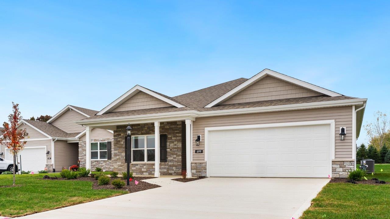 riverwalk villas harmony b3 exterior with covered patio, 2 car garage, sod yard, landscaping, heather vinyl siding, heather shake, and glacial bluff stone