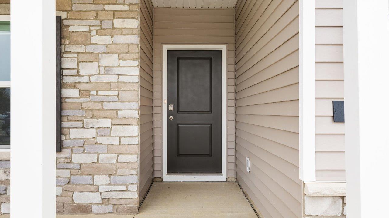 riverwalk villas harmony b3 exterior with covered patio, 2 car garage, sod yard, landscaping, heather vinyl siding, heather shake, and glacial bluff stone