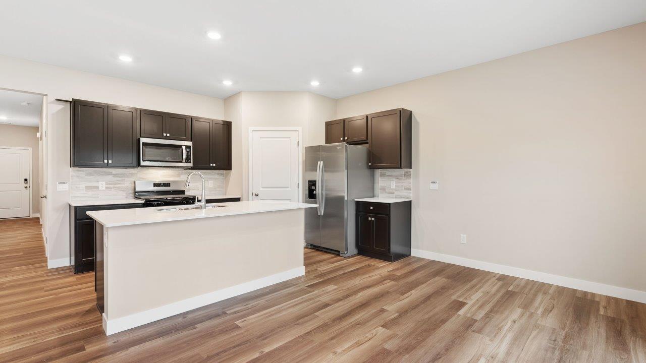 riverwalk villas harmony b3 kitchen with miami vena quartz countertops, sarsaparilla cabints, whirlpool stainless steel appliances, corner pantry, and ceramic tile backsplash