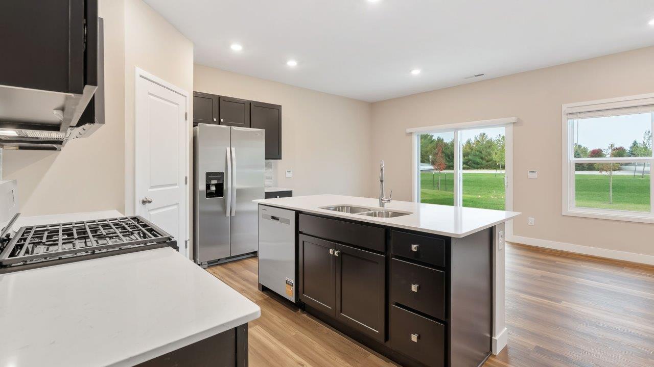riverwalk villas harmony b3 kitchen with miami vena quartz countertops, sarsaparilla cabints, whirlpool stainless steel appliances, corner pantry, and ceramic tile backsplash