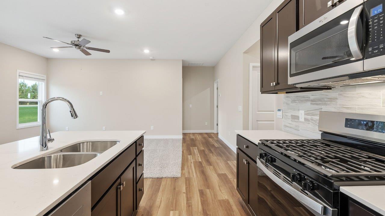 riverwalk villas harmony b3 kitchen with miami vena quartz countertops, sarsaparilla cabints, whirlpool stainless steel appliances, corner pantry, and ceramic tile backsplash
