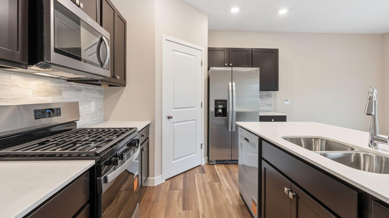 riverwalk villas harmony b3 kitchen with miami vena quartz countertops, sarsaparilla cabints, whirlpool stainless steel appliances, corner pantry, and ceramic tile backsplash