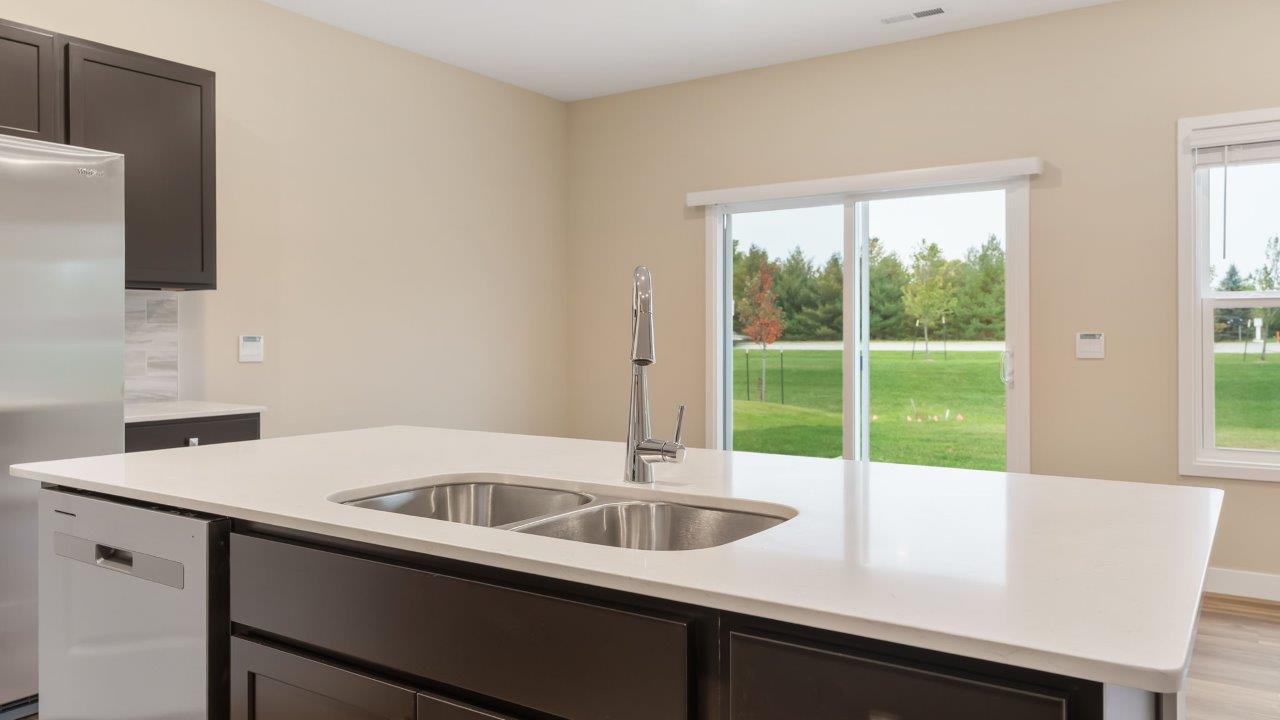 riverwalk villas harmony b3 kitchen with miami vena quartz countertops, sarsaparilla cabints, whirlpool stainless steel appliances, corner pantry, and ceramic tile backsplash