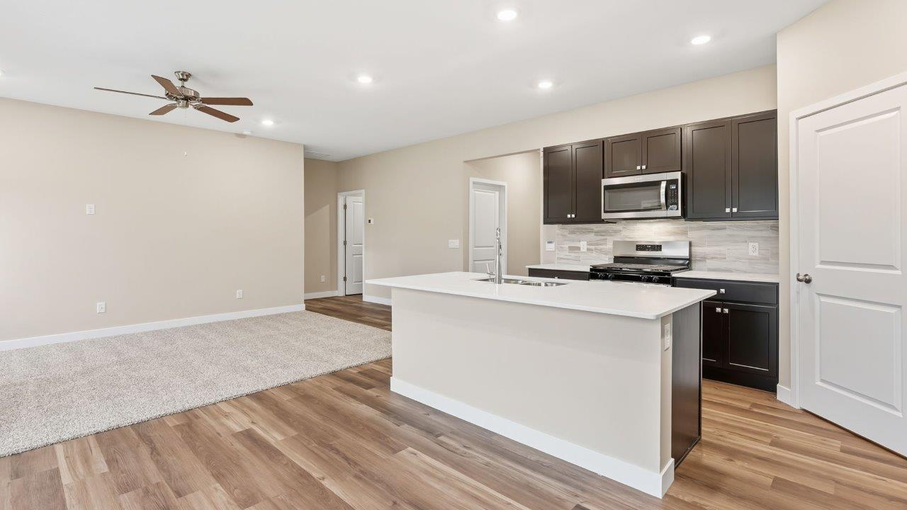 riverwalk villas harmony b3 kitchen with miami vena quartz countertops, sarsaparilla cabints, whirlpool stainless steel appliances, corner pantry, and ceramic tile backsplash