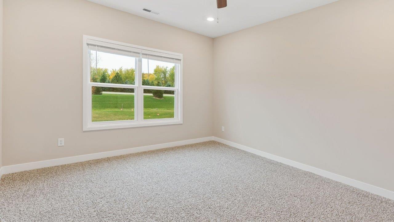 riverwalk villas harmony b3 primary bedroom with elk beige carpet flooring, ceiling fan, 2 windows, and ensuite bathroom and walk in closet
