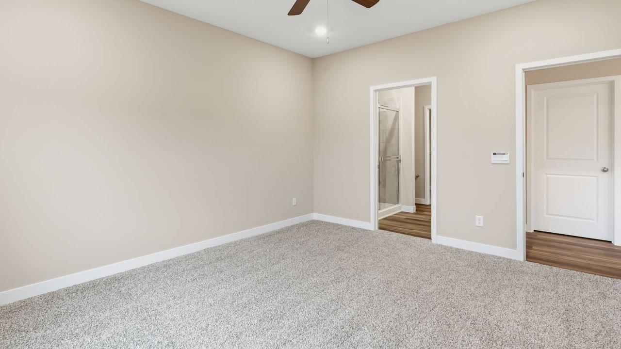 riverwalk villas harmony b3 primary bedroom with elk beige carpet flooring, ceiling fan, 2 windows, and ensuite bathroom and walk in closet