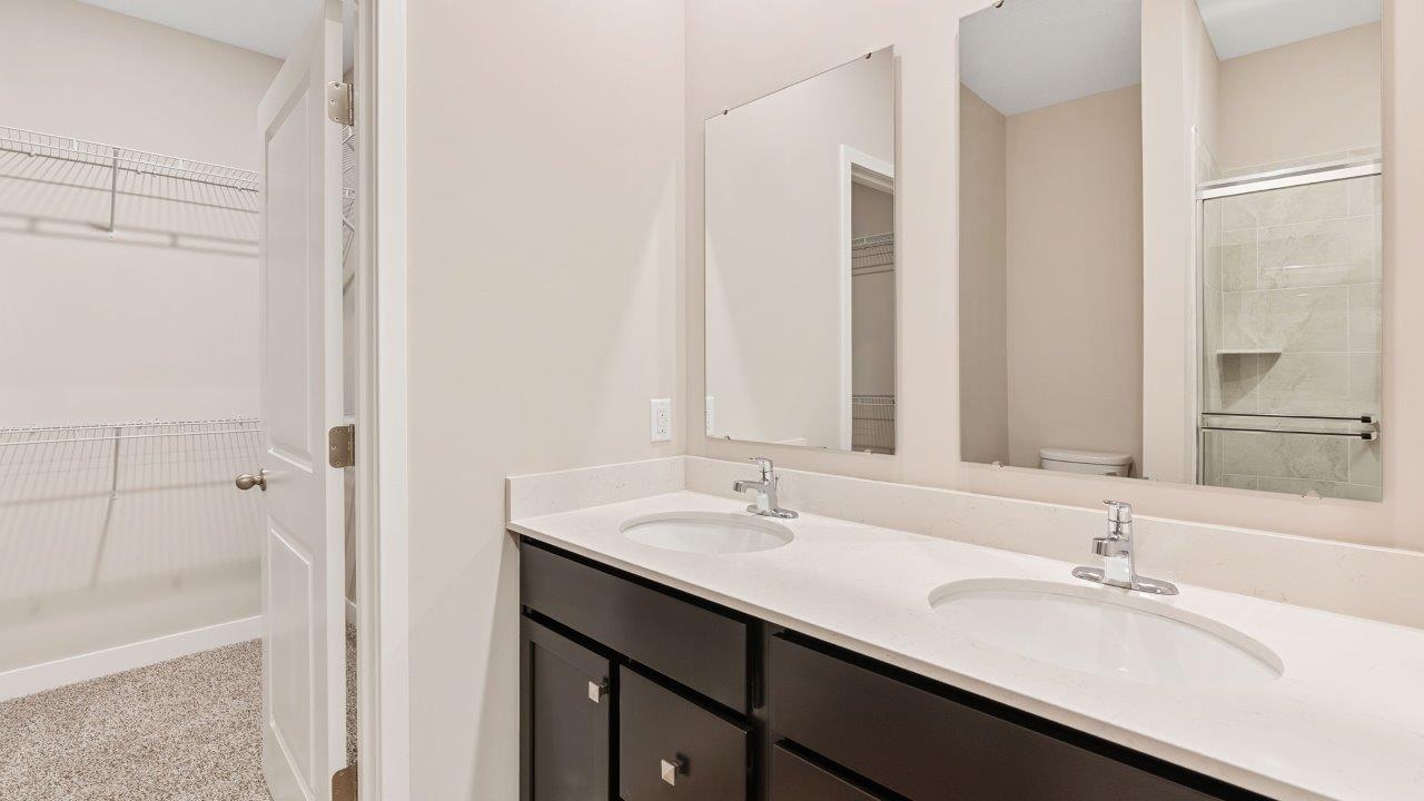 riverwalk villas harmony b3 primary bedroom ensuite bathroom with dual sink vanity, sarsaparilla cabinets, miami vena quartz countertops, walk in ceramic tile shower
