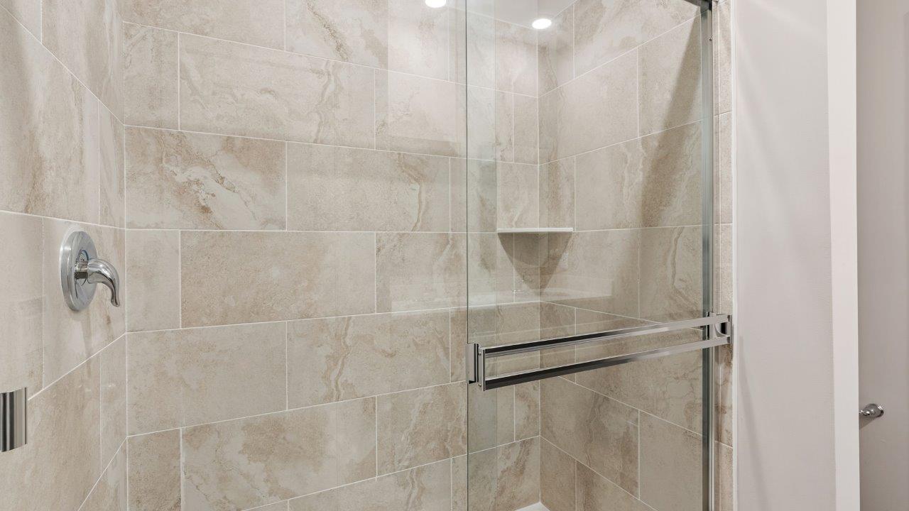 riverwalk villas harmony b3 primary bedroom ensuite bathroom with dual sink vanity, sarsaparilla cabinets, miami vena quartz countertops, walk in ceramic tile shower