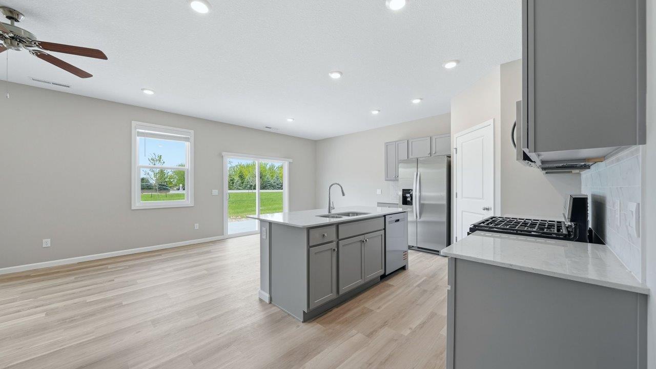 kitchen with gray cabinets, stainless steel appliances, corner pantry, and spacious center island, quartz counters, and ceramic tile backsplash