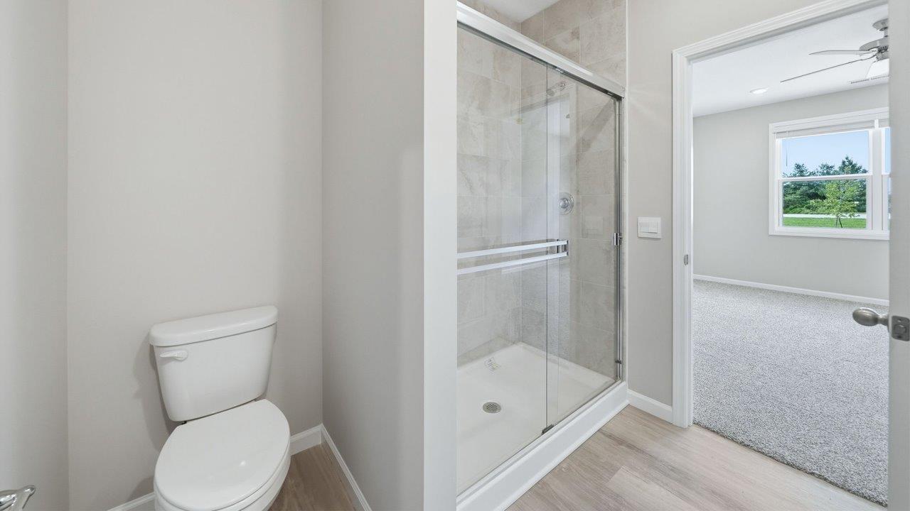 primary bedroom ensuite bathroom with dual sink vanity, ceramic tile shower, and gray cabinets
