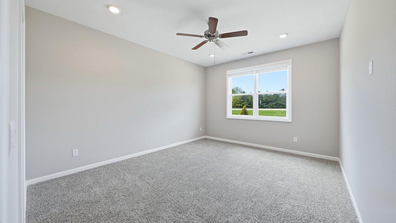 primary bedroom with carpet flooring, ceiling fan, large window, and ensuite walkin closet and bathroom
