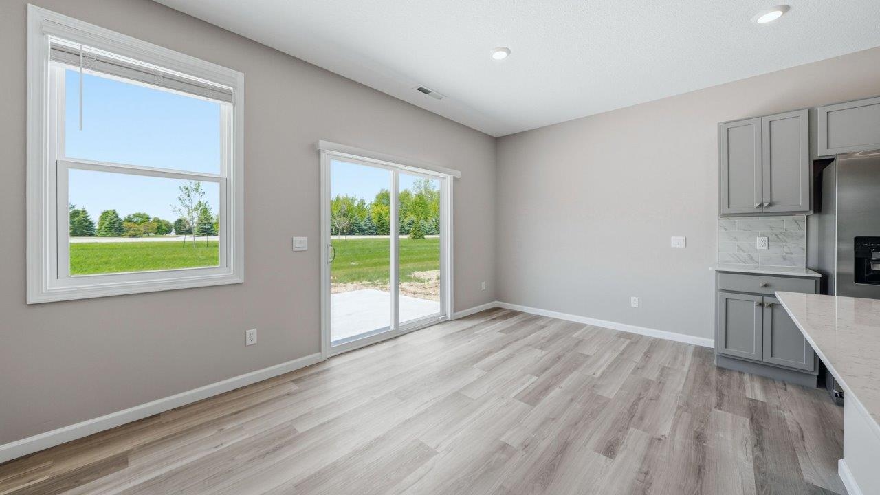 kitchen with gray cabinets, stainless steel appliances, corner pantry, and spacious center island, quartz counters, and ceramic tile backsplash