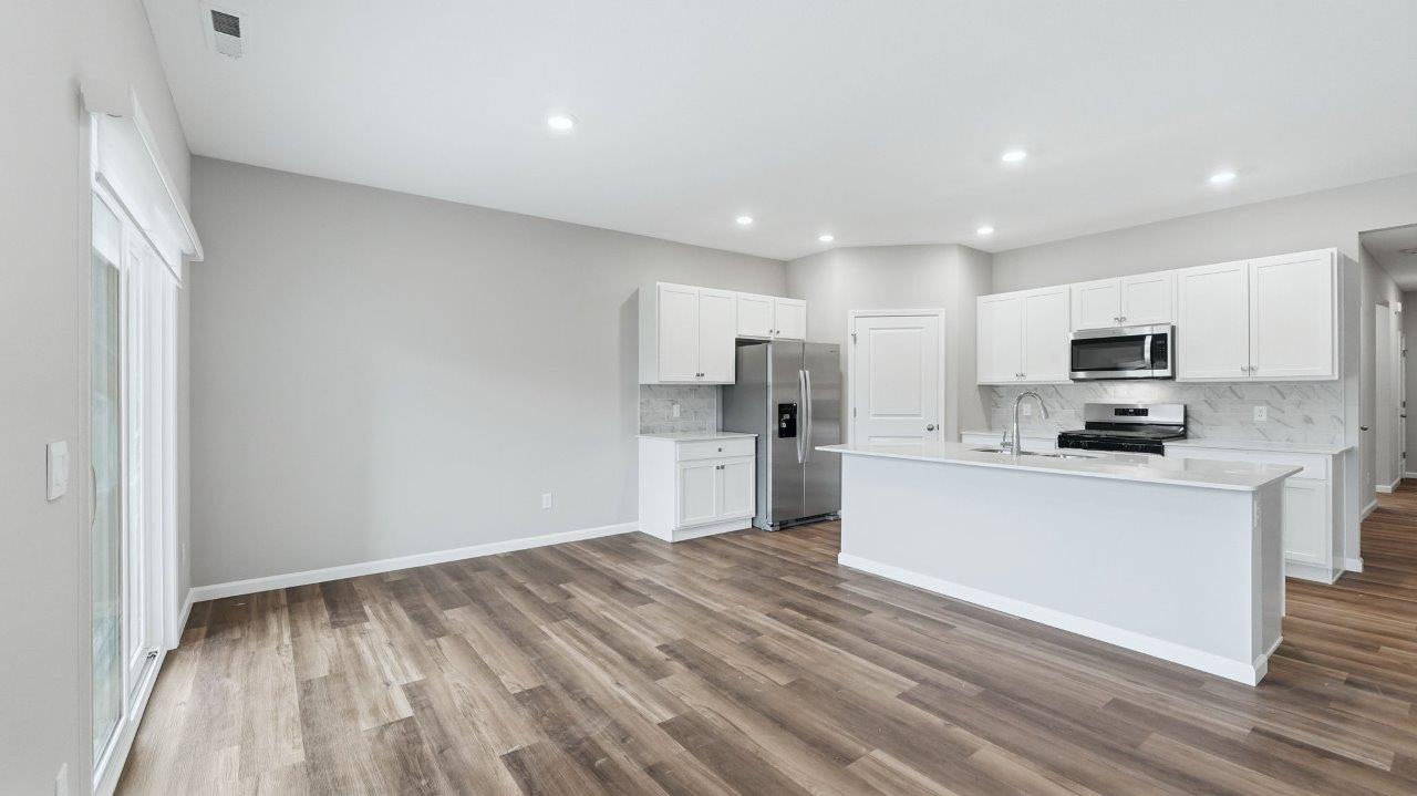 kitchen with white cabinets, stainless steel appliances, corner pantry, center island with bar seating, tile backsplash