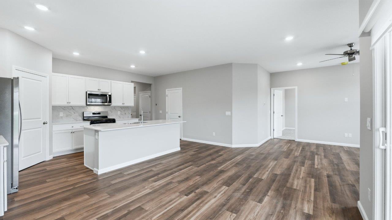 kitchen with white cabinets, stainless steel appliances, corner pantry, center island with bar seating, tile backsplash