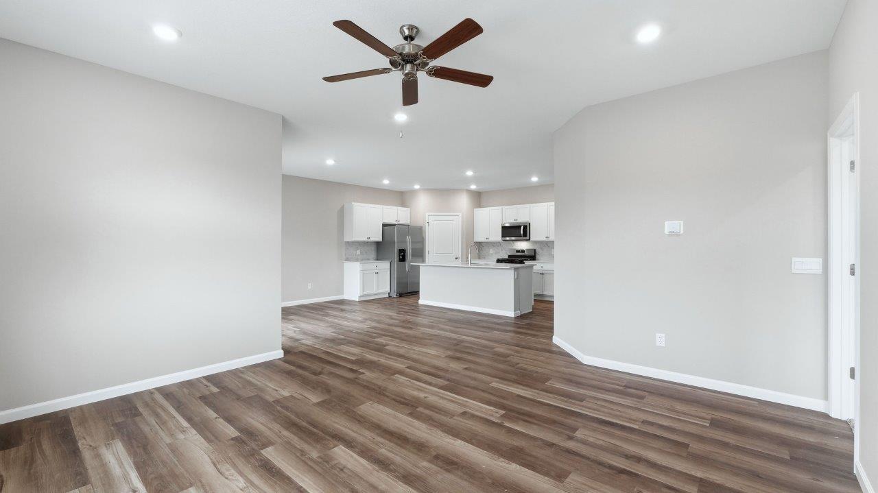 open layout living room with lvp flooring, ceiling fan, and 2 windows
