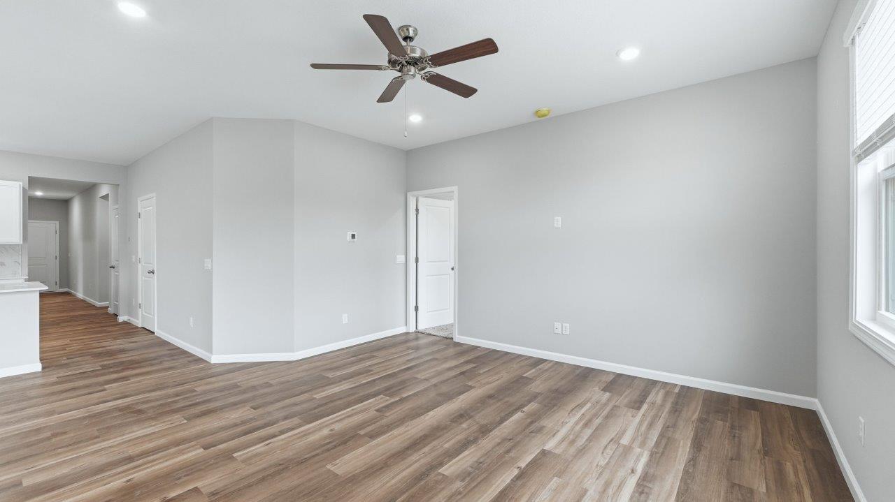 open layout living room with lvp flooring, ceiling fan, and 2 windows