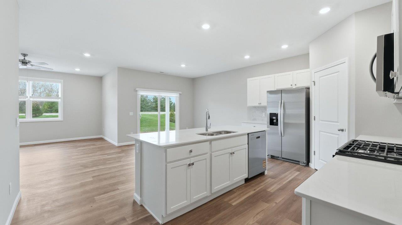 kitchen with white cabinets, stainless steel appliances, corner pantry, center island with bar seating, tile backsplash