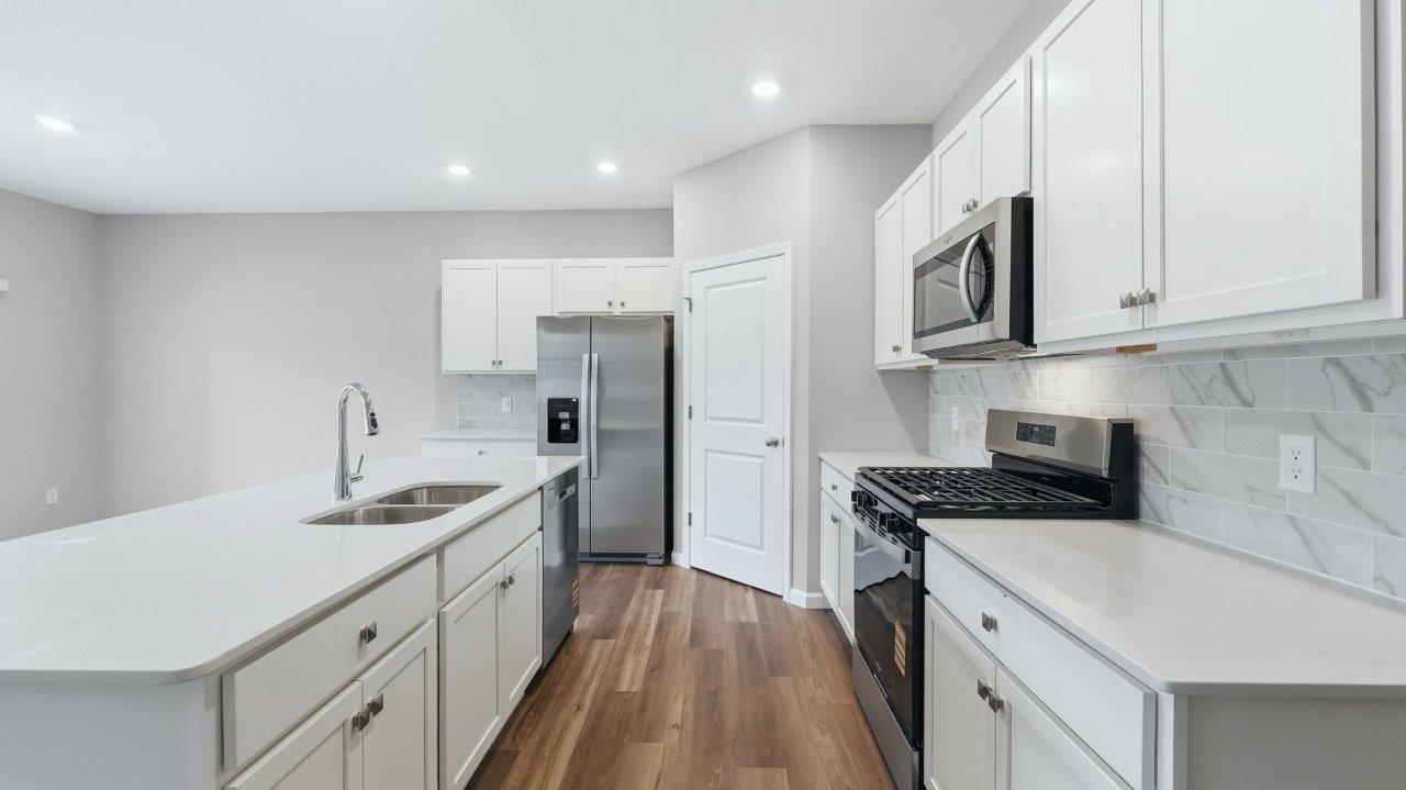 kitchen with white cabinets, stainless steel appliances, corner pantry, center island with bar seating, tile backsplash