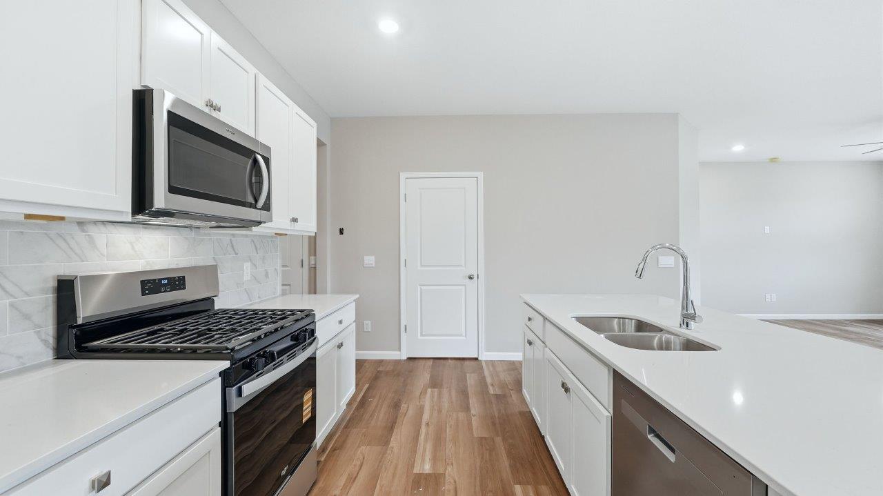 kitchen with white cabinets, stainless steel appliances, corner pantry, center island with bar seating, tile backsplash