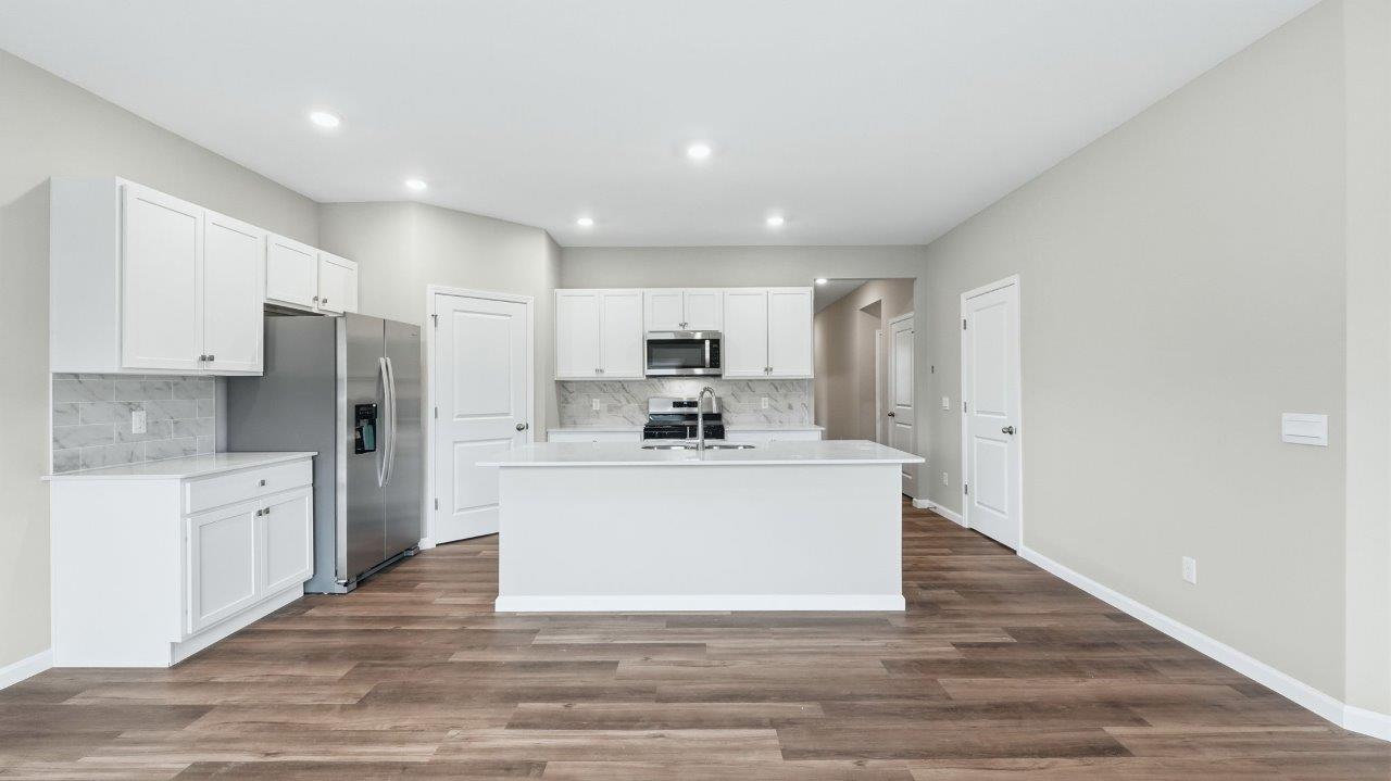 kitchen with white cabinets, stainless steel appliances, corner pantry, center island with bar seating, tile backsplash
