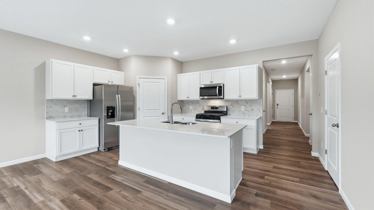 kitchen with white cabinets, stainless steel appliances, corner pantry, center island with bar seating, tile backsplash